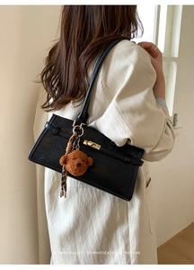 Detail of black matte tote bag with golden twist-lock and cute brown bear pendant charm