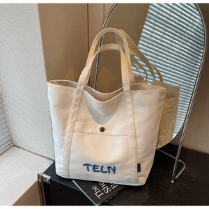 Gros plan détaillé d'un grand sac fourre-tout en toile crème avec broderie bleue 3D