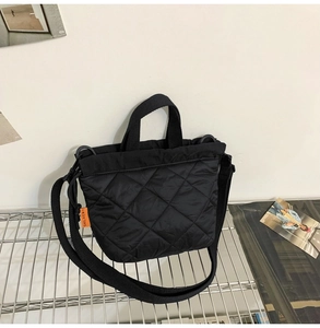 Close-up of black quilted nylon bucket bag featuring a bright orange brand side tag