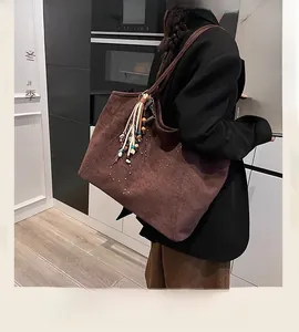 Détail du grand sac cabas en suédine marron avec rivets et pompon en situation réelle