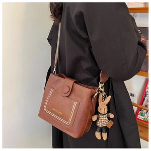 Close-up of brown vintage bucket bag with jacquard strap and cute rabbit pendant