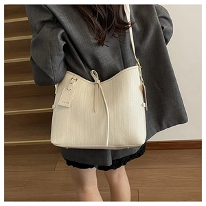 Dettaglio della borsa tote in pelle intrecciata crema con fiocco a coulisse e ciondolo