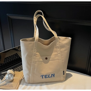 Détail du sac cabas en toile beige avec broderie TELN bleue et poche à bouton-pression