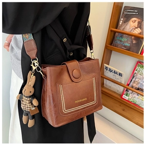 Detail of vintage brown PU leather bucket bag with stitched pocket and floral strap