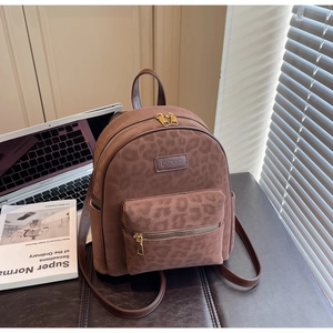 Detail of dark brown leopard print backpack with matte texture next to a laptop