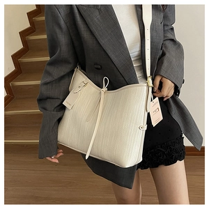 Dettaglio della borsa hobo intrecciata crema con nappe decorative e targhetta in pelle