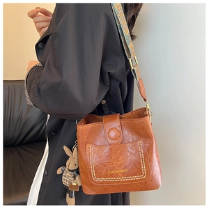 Detail of vintage brown bucket bag with bohemian strap and cute knitted rabbit charm