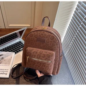 Detail view of brown leopard embossed backpack with gold zippers and side pockets