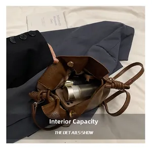 Detailed view of brown leather bucket bag interior showing phone and cosmetics capacity