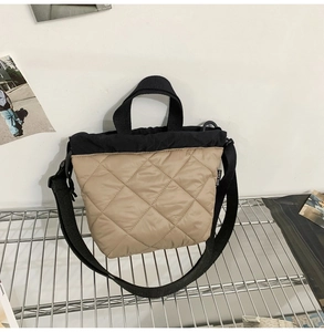 Close-up of khaki quilted nylon bucket bag with black trim and brand tag on side