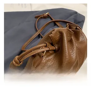Detailed macro shot of the brown litchi pattern leather bucket bag with gold hardware