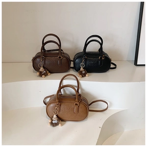 Vue détaillée de mini sacs cylindres en noir et marron avec breloques en peluche et sangles