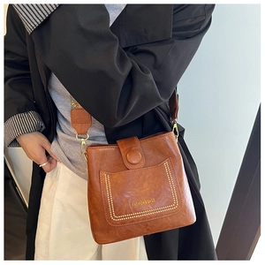 Close-up of brown vintage bucket bag featuring metal studs and a colorful woven strap