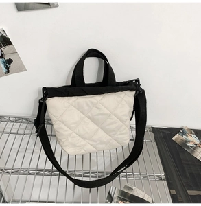 Detail of quilted beige tote bag showing high-quality stitching and black strap texture