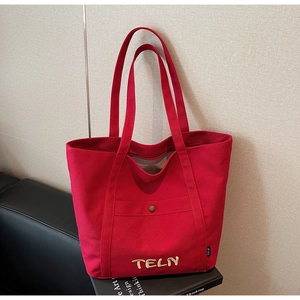 Détail d'un cabas en toile rouge avec broderie TELN 3D et poche avant à bouton pression