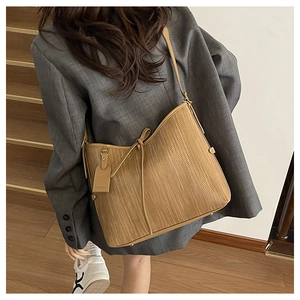 Dettaglio della trama intrecciata marrone della borsa tote con coulisse e cartellino