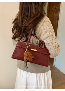 Detailed back view of a burgundy leather shoulder bag with a cute teddy bear charm