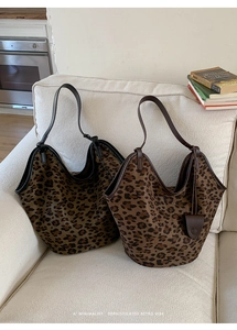 Vue détaillée de deux grands sacs hobo en daim à imprimé léopard sur un canapé neutre