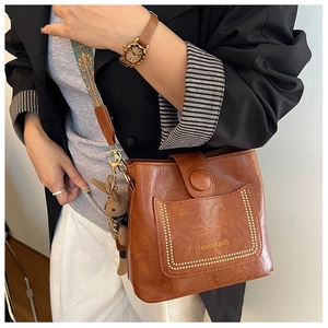Detail of vintage brown leather bucket bag with ethnic strap and rabbit charm accessory
