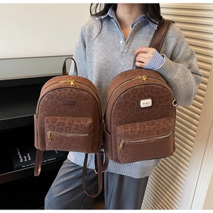 Detail view of brown leopard print backpacks in two sizes with gold zipper accents