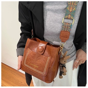Close-up of vintage brown leather bucket bag with ethnic strap and rabbit charm