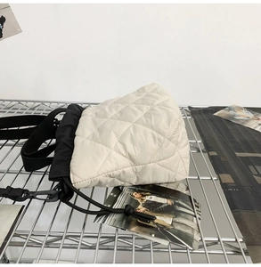 Detailed close-up of ivory quilted drawstring bucket bag on an industrial metal shelf