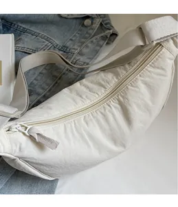 Detail of white nylon crossbody bag with textured fabric and smooth metal zipper closure