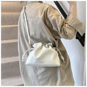 Detail of white pleated cloud bag showing fine lychee leather texture and gold logo