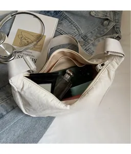 Spacious interior of beige nylon dumpling bag showing storage for phone and cosmetics