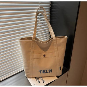 Détail du sac cabas en toile beige avec broderie TELN bleue et décor de bouton marron