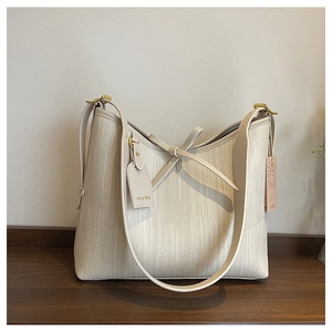 Dettaglio della trama intrecciata e fiocco in pelle crema sulla borsa hobo capiente