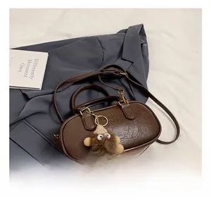 Détail du sac Boston en cuir marron rétro avec gaufrage TN et breloque peluche