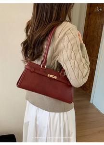 Detailed view of deep red retro leather handbag with gold twist lock and smooth finish