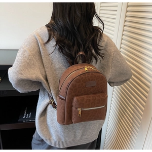 Brown leopard print backpack featuring a matte suede texture and gold zippers for travel