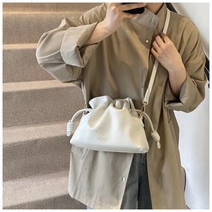 Close-up of white lychee texture leather bucket bag with elegant pleats and gold buckle