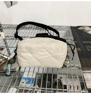 Detail of quilted nylon bucket bag in cream with black drawstring and woven strap