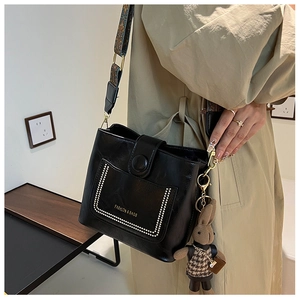 Detail of black matte bucket bag featuring metal rivets and vintage jacquard strap