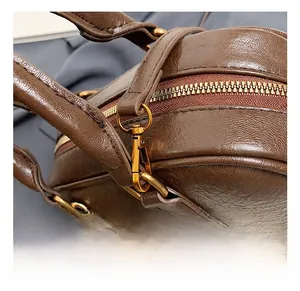 Détail de la texture en cuir marron et du crochet en métal doré de ce sac à main