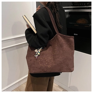 Détail d'un grand sac cabas en daim marron foncé avec rivets et pendentif à perles