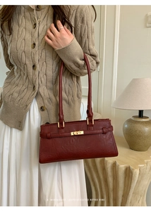 Detail shot of vintage dark red tote bag featuring gold metal twist-lock and slim handles