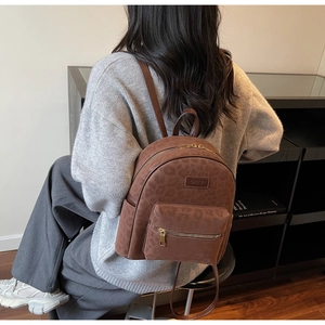 Detailed view of brown leopard embossed backpack featuring a front pocket and gold hardware