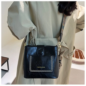 Detail of black leather bucket bag featuring white beaded pocket and vintage jacquard strap