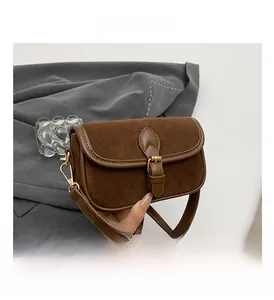 Detail of dark brown matte leather shoulder bag featuring heart stitched strap and gold buckle
