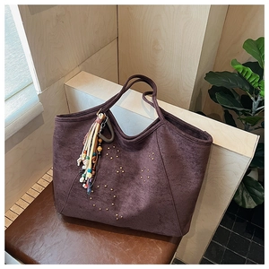Détail du grand sac cabas en daim prune avec rivets dorés et pompon perlé ethnique