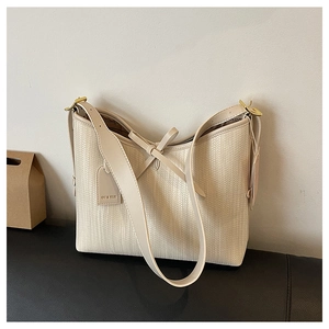 Dettaglio della borsa hobo intrecciata beige con fiocco decorativo e tracolla larga