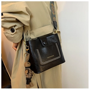 Detail of black pebbled leather bucket bag with ethnic woven strap and rabbit charm