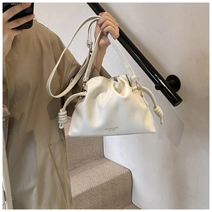 Detailed shot of beige lychee texture leather shoulder bag with cloud pleats and knot