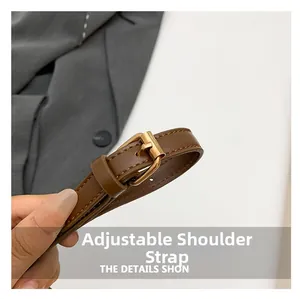 Detail of adjustable brown leather shoulder strap with a polished gold-tone metal buckle