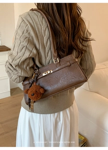 Detail of vintage brown faux leather shoulder bag with metal lock and bear charm