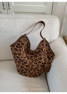 Détail du sac cabas vintage en daim à imprimé léopard avec anses en cuir sur un canapé
